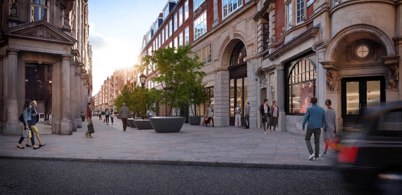A computer generated visual of the proposals for Basil Street from the Sloane Street end. The footway now crosses the entrance to the road so no vehicles can drive through. The footway has new natural stone paving.  To the centre of the street are new trees in large round pots.  CGI people are dotted throughout the street, enjoying the new streetscape.– visualised view from Sloane Street 