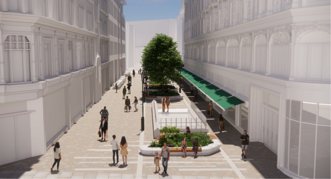 This is an image looking down Hans Crescent from Brompton Road towards Basil Street. A large stone planter is visible in the foreground positioned between the footway on Brompton Road and the entrance to the Underground station. There is timber seating with arm rests on the rim of the planter for visitors to rest. A new paving pattern in natural stone is evident on the floor. In the background a line of large planters with trees and shrubs can be seen, positioned centrally, along the length of the street. An area of clear pavement adjacent to the top of the entrance steps to the Underground station is shown.  The cafés facing Harrods are shown with tables and chairs directly in front of their shopfronts. The area between these tables and chairs and the proposed central planters is clear. Pedestrians can be seen walking on this broad clear path towards Basil Street, which is visible in the distance. New heritage style lamp columns can be seen. 