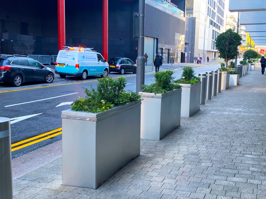 This is a photo of concrete planters lined along the kerb line used to stop vehicles from mounting pavements. 