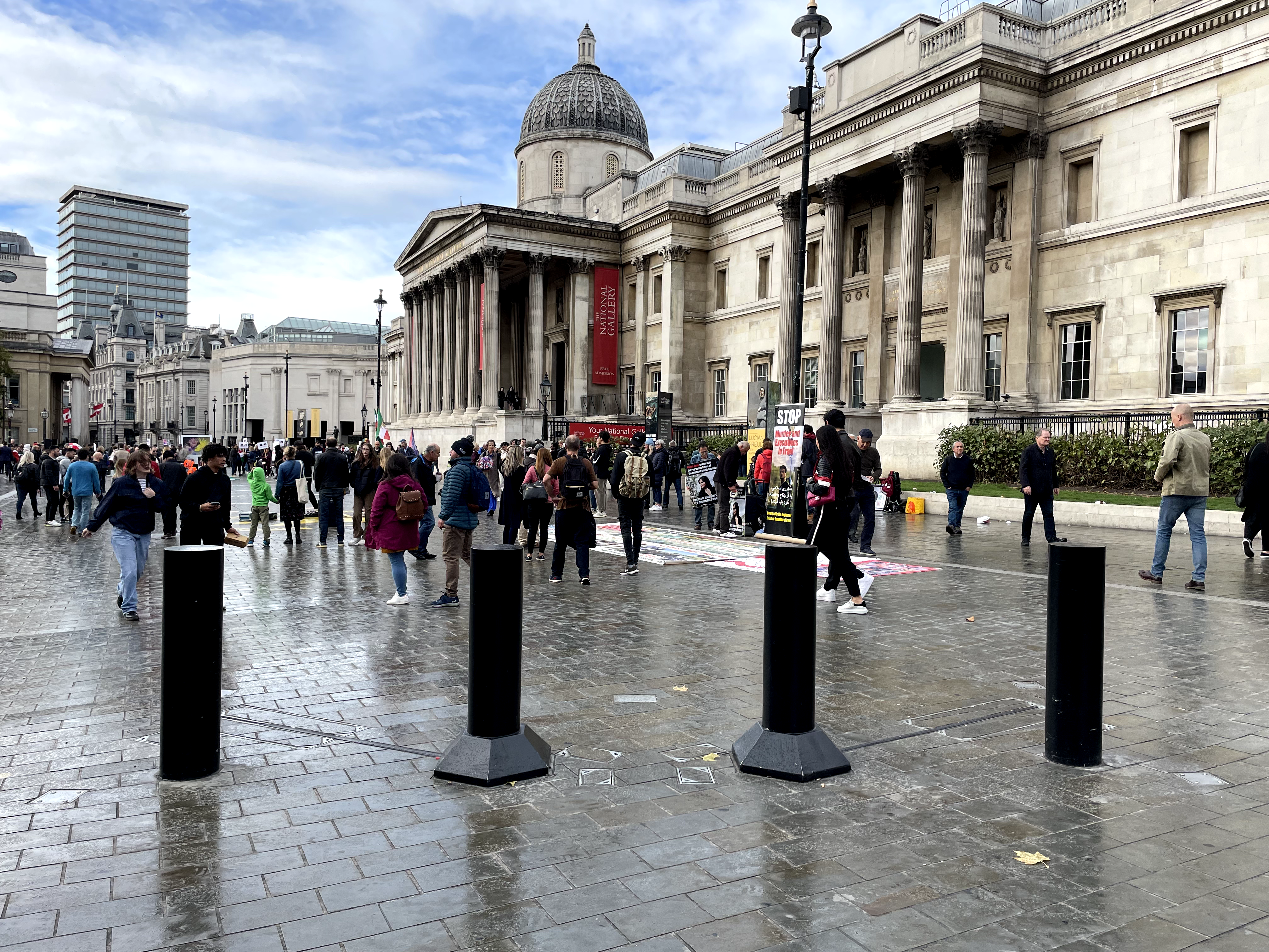 This is a photo of Trafalgar Square showing black sliding bollards at the forefront and the National Gallery in the background.